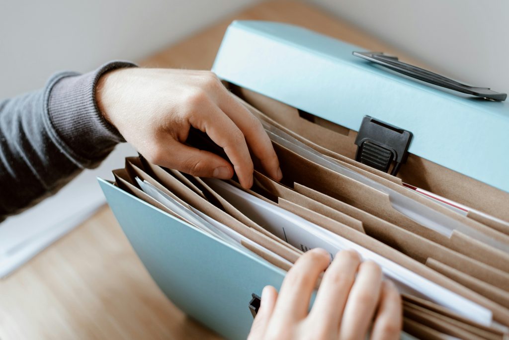 Close-up of hands organizing papers in a blue folder, ideal for business and office concepts.