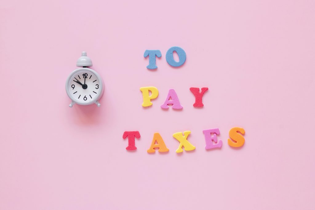 Creative tax payment reminder with clock and colorful letters on a pink background.