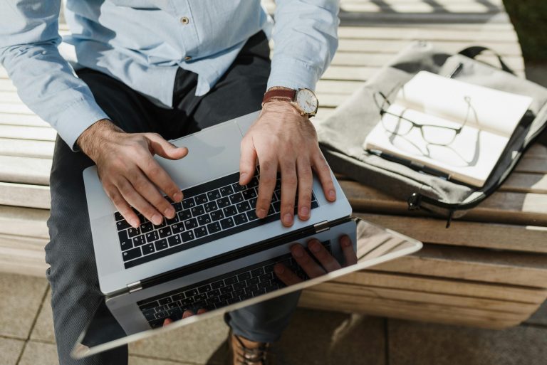 Man working on a laptop outdoors, embracing remote work lifestyle. High angle view.