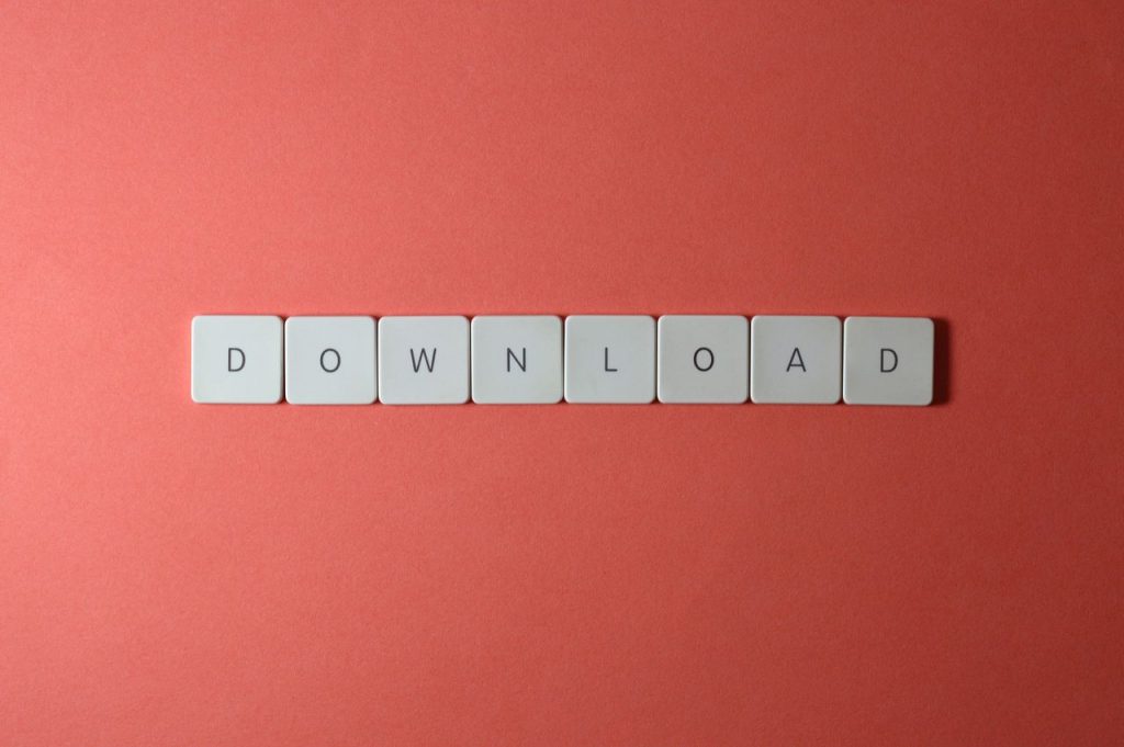 Minimalist photo of keyboard tiles spelling 'DOWNLOAD' on a red background.